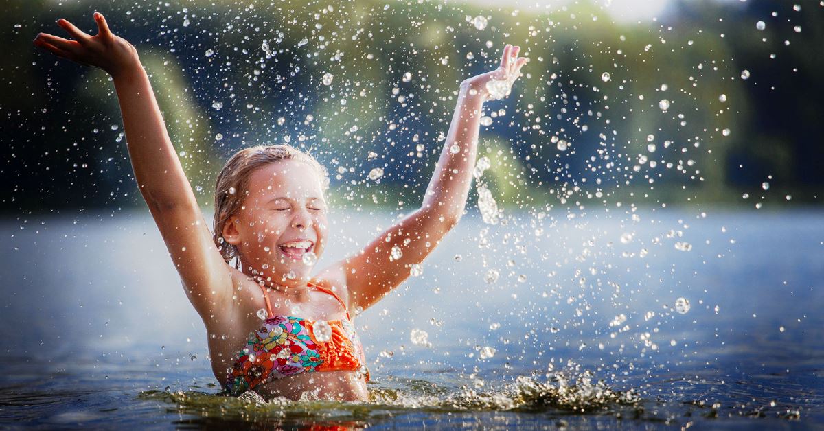 girl splashing in a lake happy